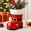 LUMIDED® Santa boot Christmas ceramic vase full product view on linen table with red berries, white wax flowers and pine cone arrangement, Christmas gifts and candle in background